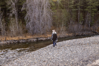 USA, Idaho, Sun Valley, Rear view of woman in wool poncho on riverbank