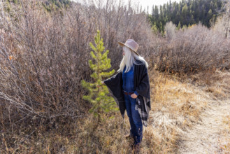 USA, Idaho, Sun Valley, Woman in wool poncho on footpath in landscape