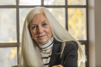USA, Idaho, Boise, Portrait of smiling senior woman with long white hair in office
