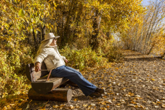 USA, Idaho, Bellevue, Senior woman relaxing on bench in landscape in autumn