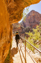 USA, Utah, Zion National Park, Smiling woman in poncho and hat hiking in Zion Overlook Trail