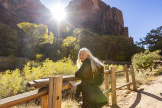 USA, Utah, Zion National Park, Senior woman leaning on fence on trail to Angels Landing
