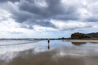 Costa Rica, Guanacaste, Playa Grande, Woman walking on empty beach at low tide