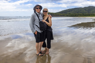 Costa Rica, Guanacaste, Playa Grande, Portrait of smiling senior couple on empty beach at low tide
