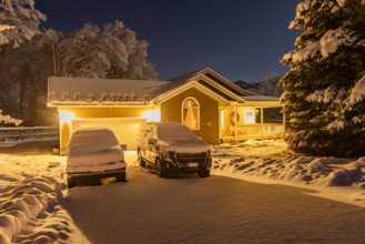 USA, Idaho, Bellevue, Illuminated suburban house and cars covered with snow at night