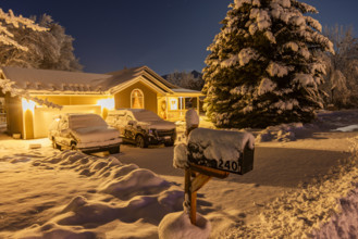 USA, Idaho, Bellevue, Illuminated suburban house and cars covered with snow at night