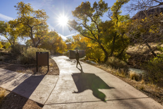 USA, Utah, Zion National Park, Senior woman in poncho making shadows on park walkway