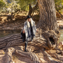 USA, Utah, Zion National Park, Portrait of smiling senior woman in poncho sitting by tree along