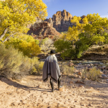 USA, Utah, Zion National Park, Rear view of woman in poncho and hat standing near Virgin River
