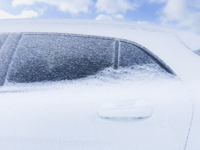Close-up of compact SUV frozen in snow and ice