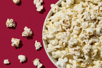 Overhead view of bowl of popcorn on red background