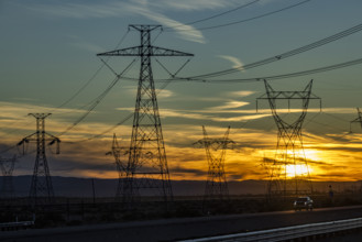 USA, California, Barstow, Electricity pylons and power lines at sunset