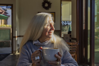 Portrait of smiling senior woman holding mug of coffee at home