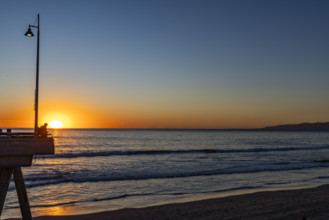 USA, California, Venice, Sun setting above calm ocean and Venice Pier