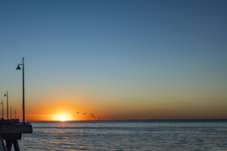 USA, California, Venice, Sun setting above calm ocean and Venice Pier