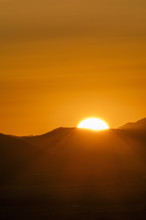Sun setting above hills against orange sky. Bellevue, Idaho, USA.
