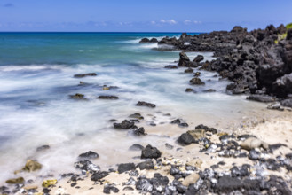 Motion blurred ocean waves washing rocks on beach. Kona, Hawaii, USA.