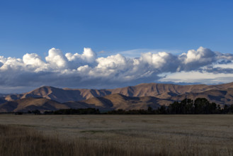 White puffy clouds over mountains and field. Bellevue, Idaho, USA.