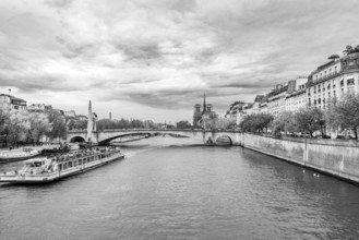 Sightseeing boat on Seine River at Ile Saint-Louis, black and white. Paris, Ile de France, France.