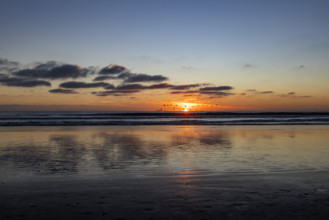 Sun setting over calm ocean. Oceanside, California, USA.