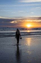 Rear view of woman walking on beach at sunset. , Guanacaste, Costa Rica.