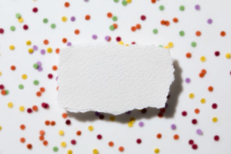 Torn white paper on confetti background. New York City, New York State, USA.
