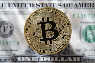 Bitcoin against one US Dollar bill. New York City, New York State, USA.