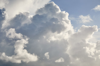 White puffy cumulous clouds and blue sky. New York City, New York State, USA.