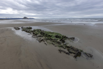 Storm clouds above beach with Morro Rock in distance, Morro Bay, California, USA.