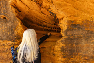 Senior blonde woman touching sandstone formations, Zion National Park, Utah, USA.