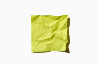 Crumpled yellow post it note on white background, New York City, New York, USA.