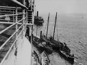 Transbordeurs et navire-citerne ravitaillant le RMS Majestic en eau douce et victuailles