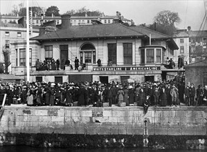 Foule de passagers attendant d’embarquer à bord d'un transbordeur, sur les quais de Queenstown en Irlande