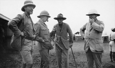 European settlers, Kenya. Exterior shot of four mature European men engrossed in conversation. All