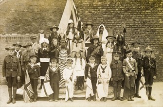 Children of the British Empire. A group of children holding union jack flags pose for a portrait,