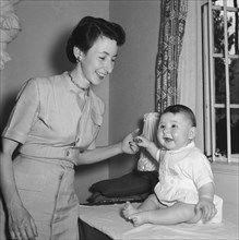 Playing with Tubby Block's baby. Interior shot of a smiling woman holding hands with Tubby Block's