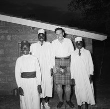 Christening cheer. Exterior night shot of Peter Buchanan and three African servants, all smiling