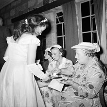 Anyone for cake?. A bridesmaid offers cake to a group of smoking female guests at the
