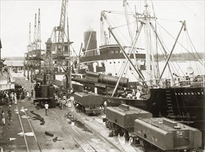 Unloading a locomotive boiler from SS Harmonides. Cranes onboard the SS Harmonides lower a train