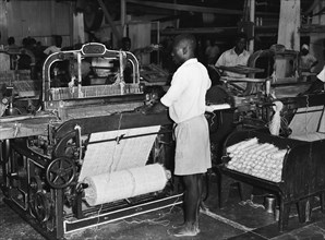 Sisal weavers. A barefoot factory worker operates a weaving machine at Sisal Products Ltd. Grown