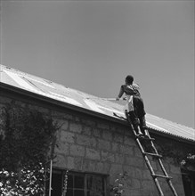 Name painting. A man on a ladder paints the name 'GABB' in large letters on the pitched roof of a