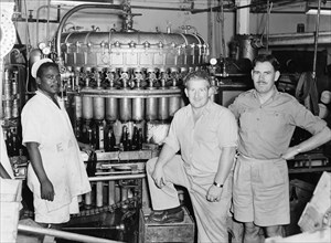 EA Breweries. Three men stand next to brewing machinery at an EA Breweries factory. The black