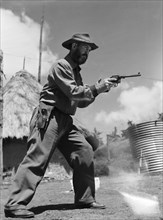 Davo' Davidson takes aim. Davo' Davidson aims a revolver. Kenya, 22 May 1953. Kenya, Eastern