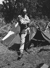 Uniformed soldier at a KAR camp. A uniformed European soldier stands outside a tent at a bivouac