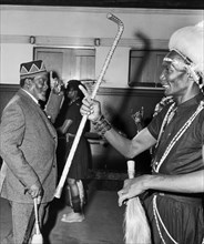 Jomo Kenyatta salutes a female bodyguard. An African man wearing traditional dress in the