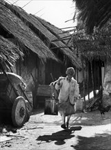 Street scene in old Mombasa. An Indian man, barefoot and wearing a turban, walks down a narrow,