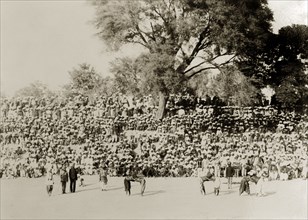 Indian wrestling competition. A large audience of turbaned Indian men gather on a slope to watch a