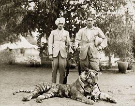 Tiger kill. Two Indian men in Western dress pose proudly over their recent tiger kill, cigar and