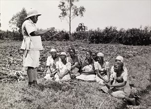 Farming advice for women. A man in uniform dispenses advice on improved farming methods to a small