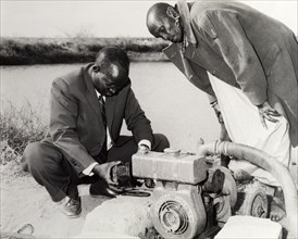 Reservoir water pump. A interested by-stander observes as a man in a suit inspects a reservoir pump